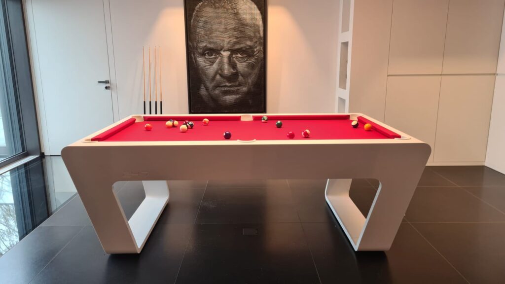 White 724 billiard table with a red playing surface in a modern private villa interior.