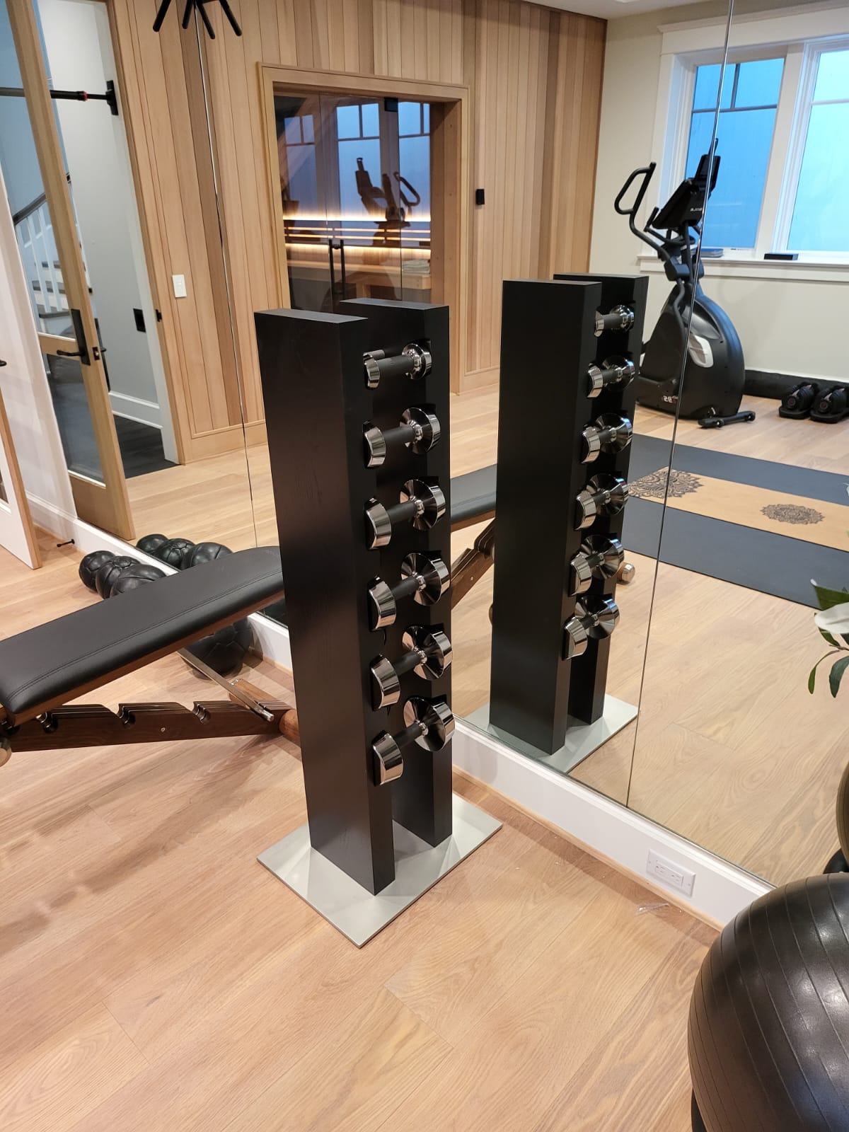 Modern home gym featuring a 724 dumbbell rack and fitness equipment in a wood-floored interior.