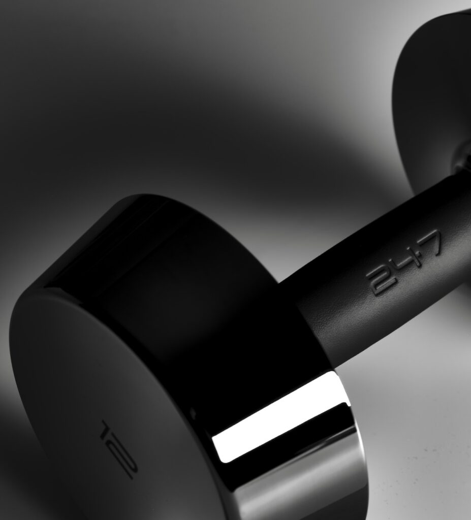 Black dumbbell with a textured handle and polished chrome weight plates on a dark background.
