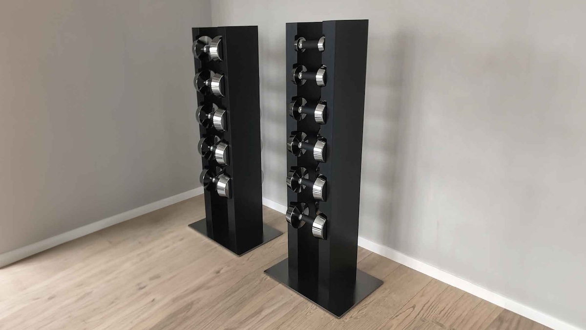 Black freestanding pool cue racks with metallic holders displayed in a modern room with light wood flooring.