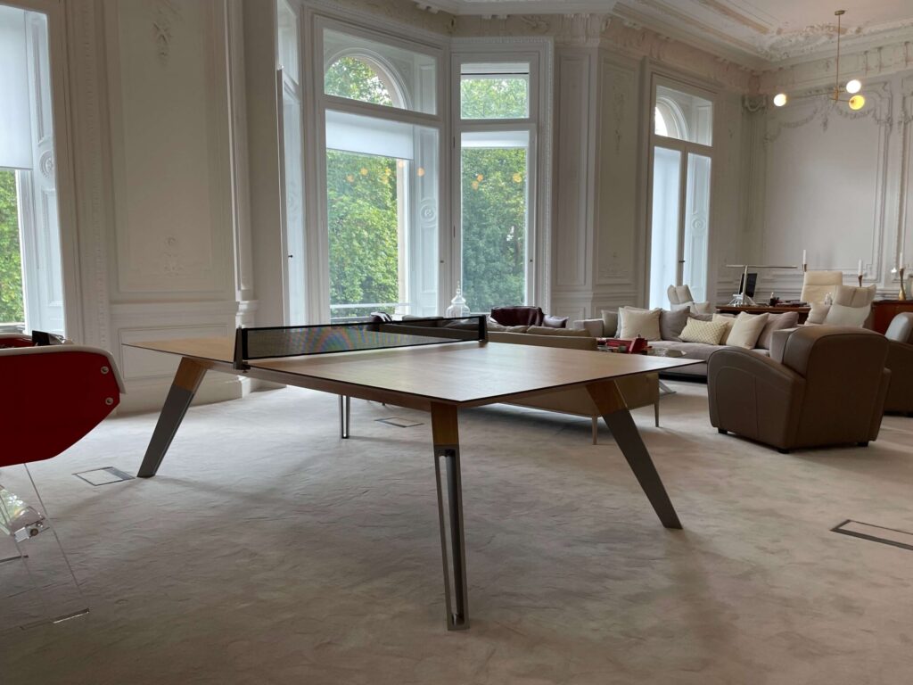 Modern ONA table tennis table with a net in an elegant, spacious living room.