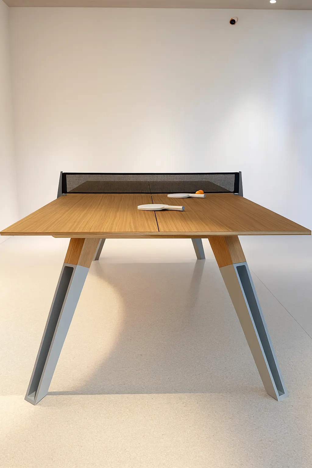 Modern wooden table tennis table with paddles and ball in a minimalist interior.