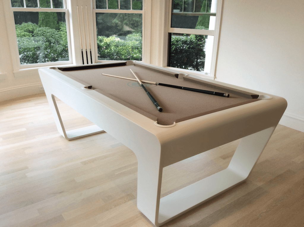 White luxury pool table with two cues in a bright, elegant interior.