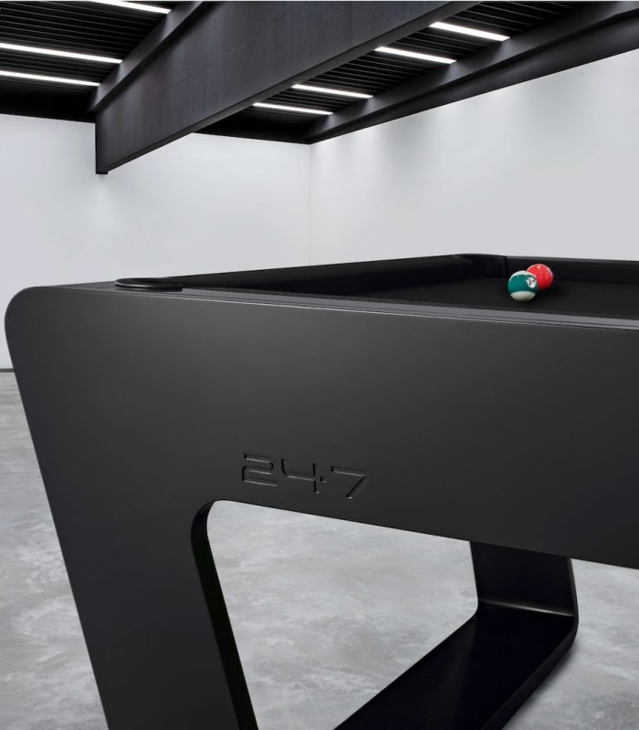 Close-up of a black 724 pool table with billiard balls in a modern industrial interior.
