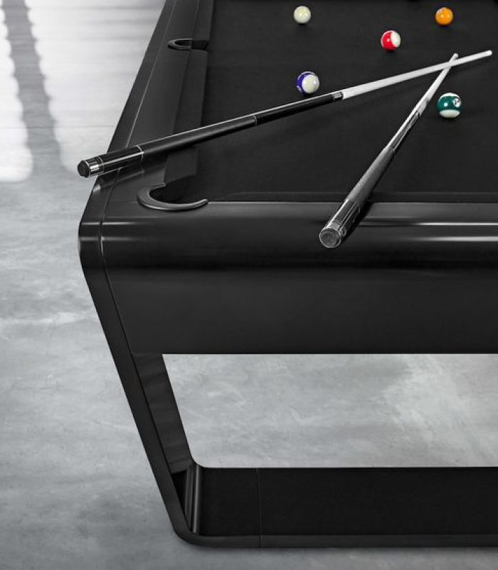 Close-up of a black pool table with billiard balls and two cues.