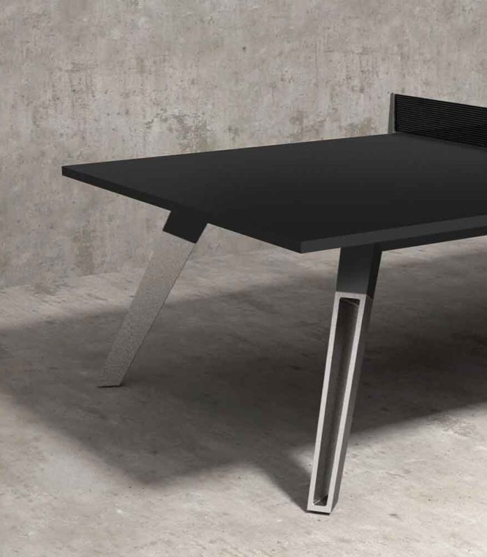 Close-up of a modern black table tennis table with angular legs in an industrial interior.