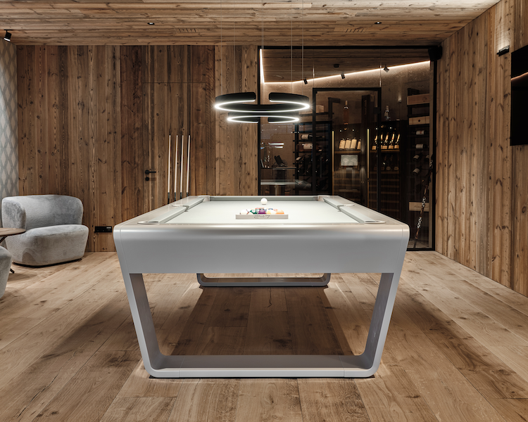 Modern white billiard table in a warm wood-paneled luxury interior with contemporary lighting.